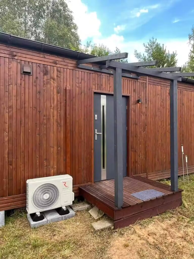 Montaż klimatyzacji z widocznym agregatem przy wejściu do domku letniskowego